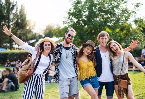 Group of cheerful young friends at summer festival, looking at camera.