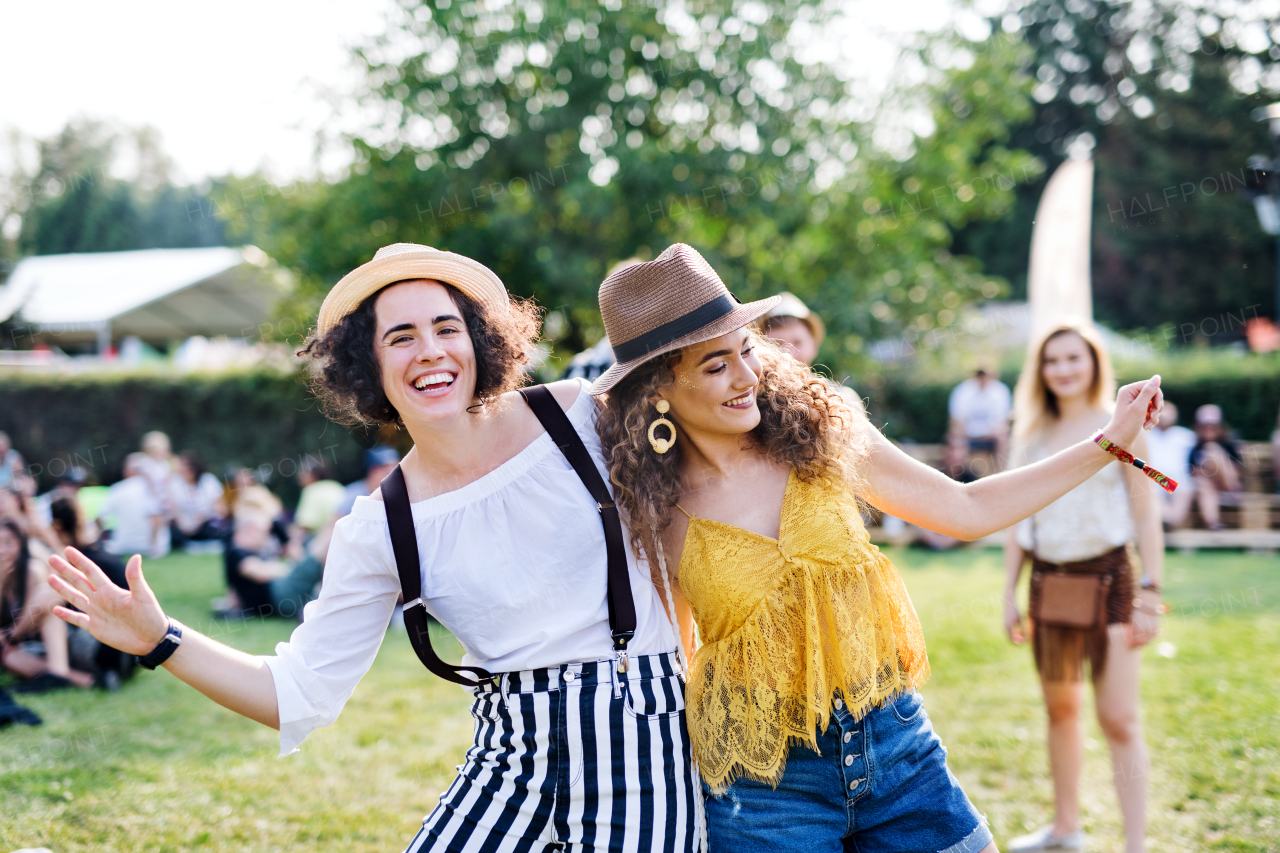 Portrait of two young women friends standing at summer festival, dancing.