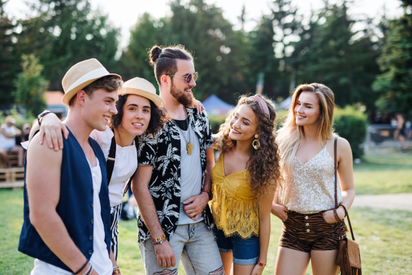 Group of cheerful young friends at summer festival, talking.