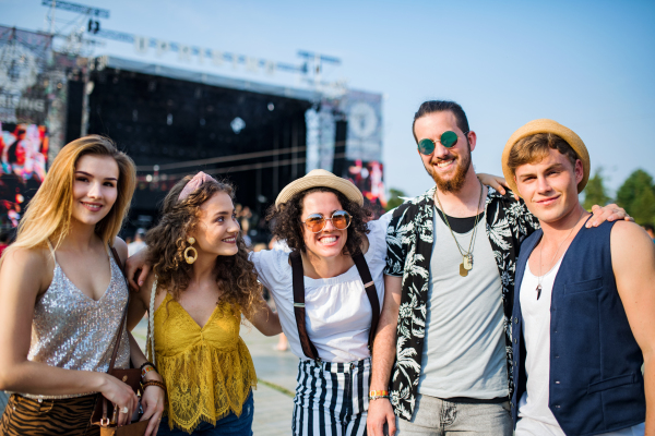 Group of cheerful young friends at summer festival, looking at camera.