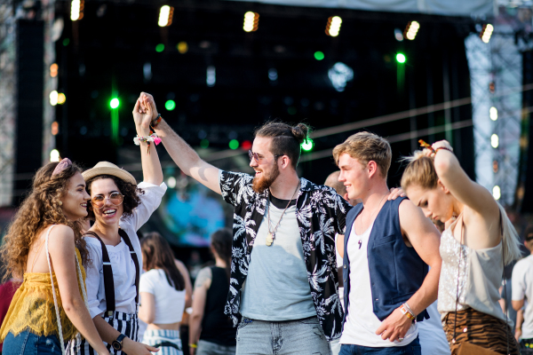 A group of cheerful young friends dancing at summer festival.