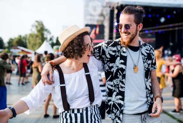 Front view portrait of young couple at summer festival, walking arm in arm.