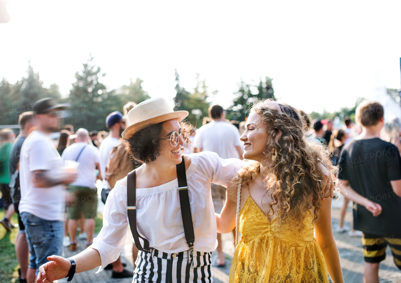 Two young women friends walking arm in arm at summer festival.