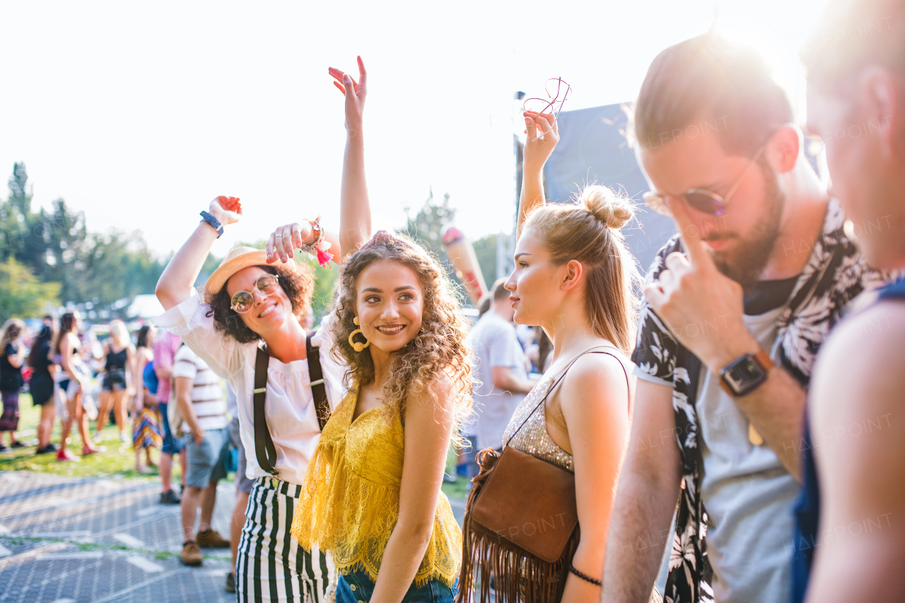 A group of cheerful young friends dancing at summer festival.