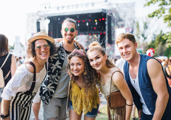 Group of cheerful young friends at summer festival, looking at camera.