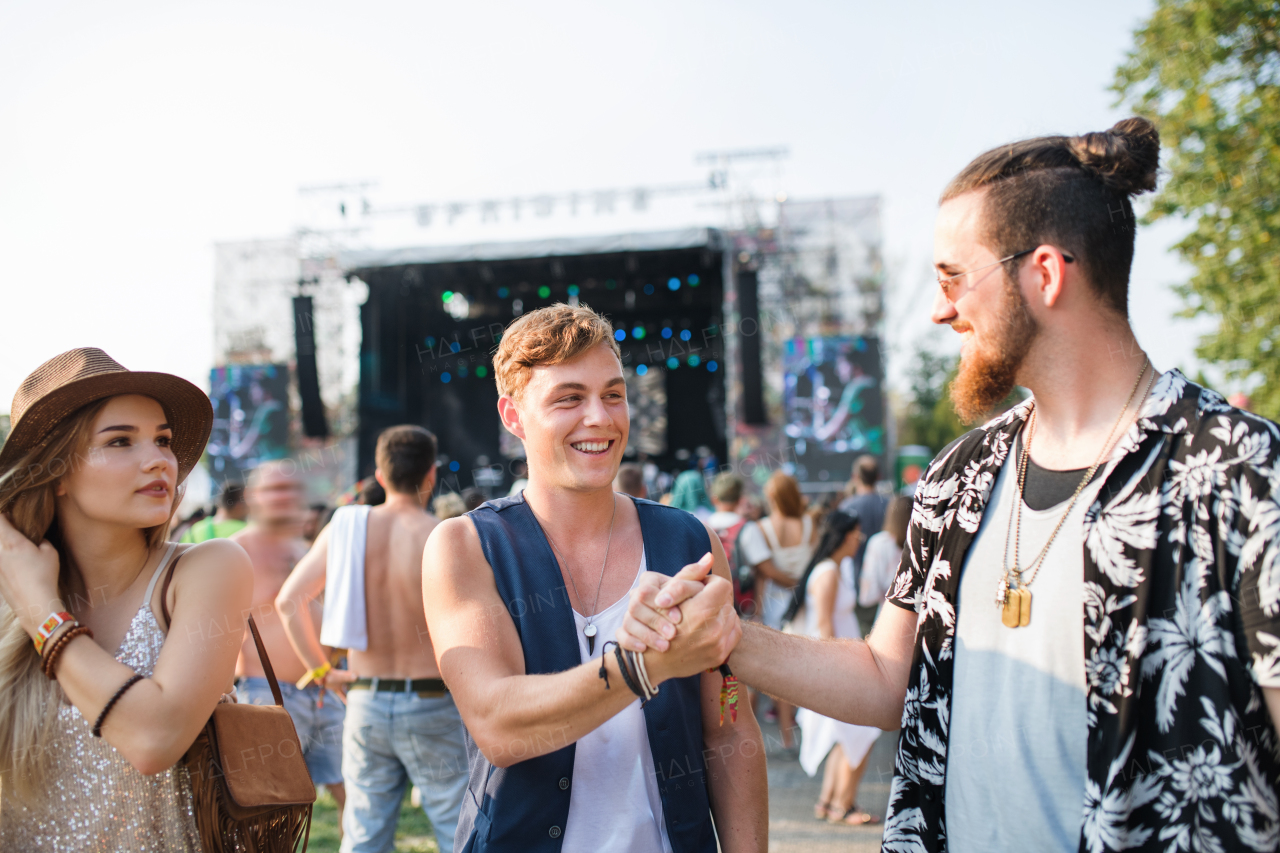 Group of cheerful young friends at summer festival, greeting.