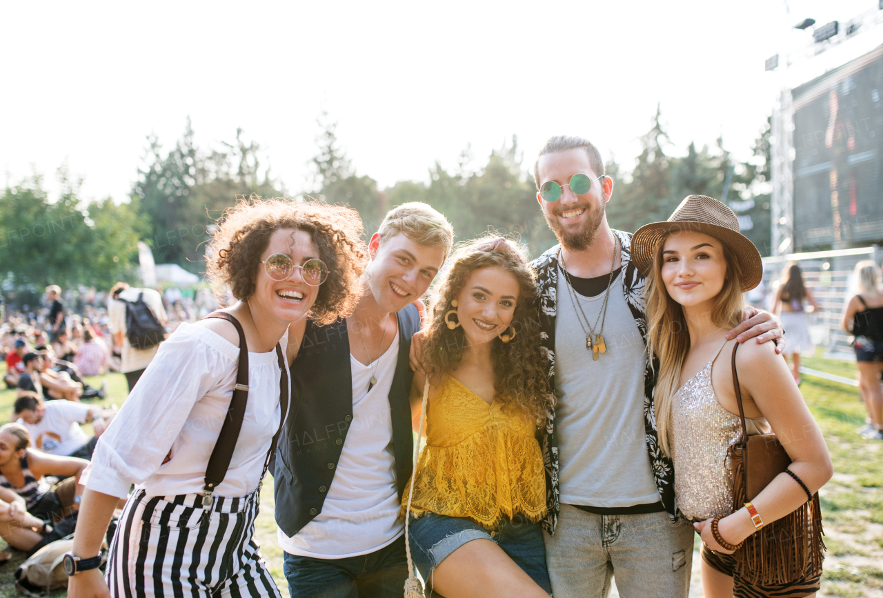 Group of cheerful young friends at summer festival, looking at camera.