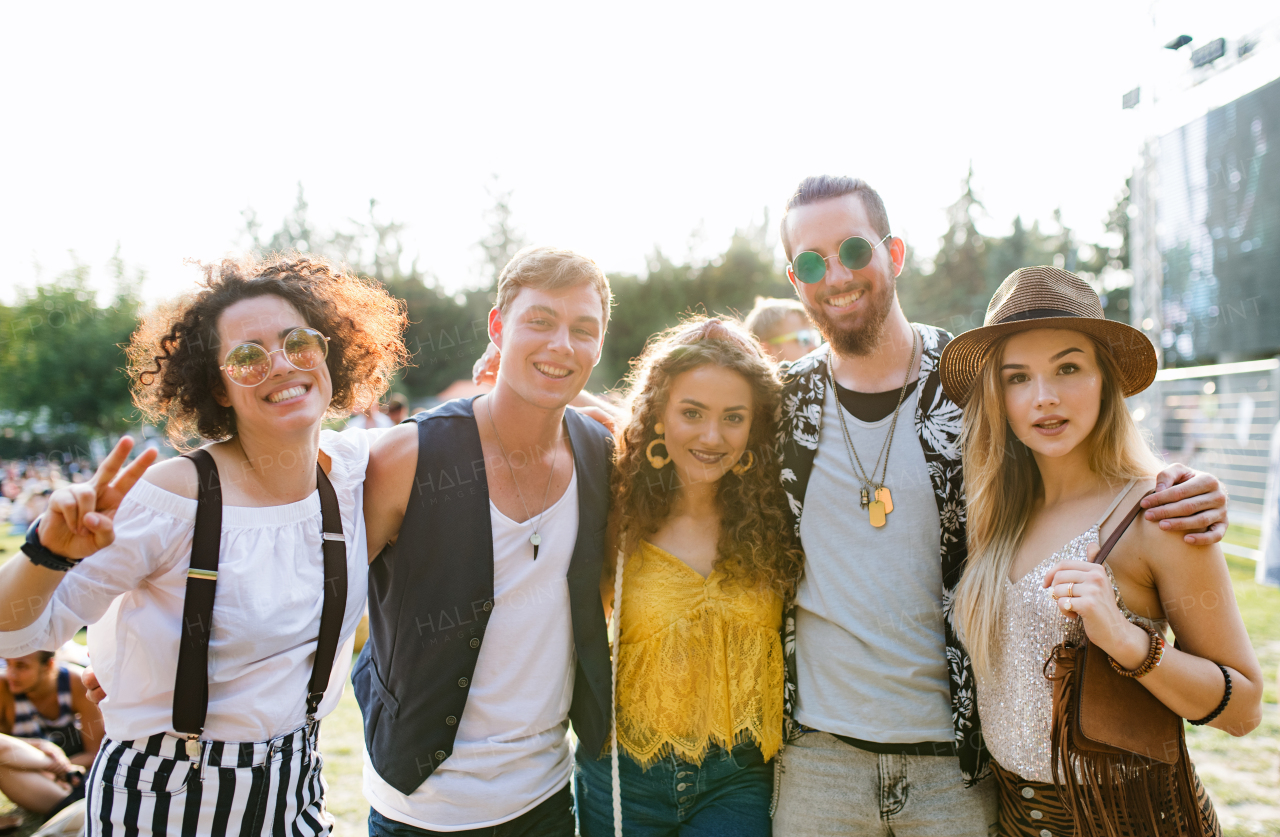 Group of cheerful young friends at summer festival, looking at camera.