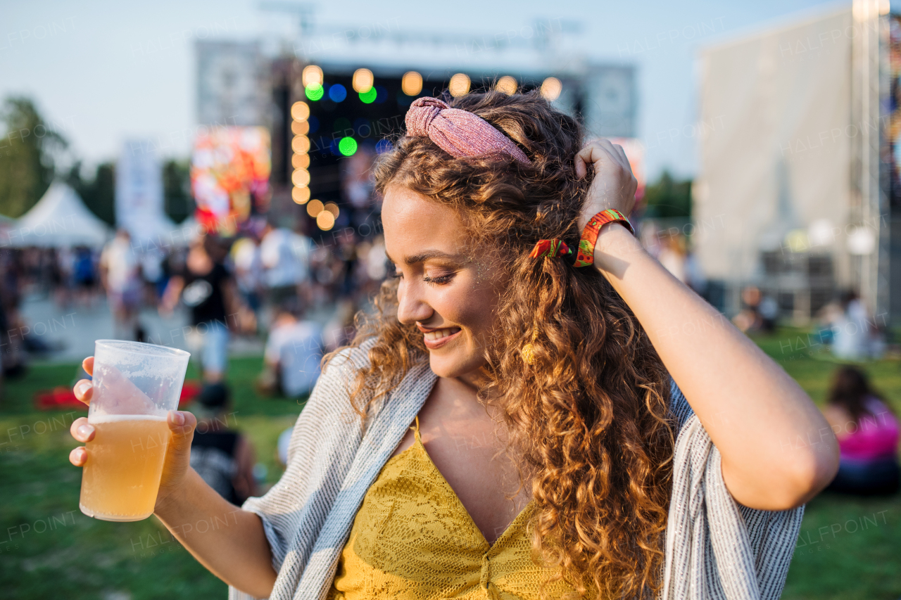 A front view of young woman with drink dancing at summer festival.