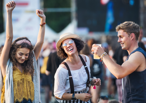 Group of cheerful young friends at summer festival, having good time.