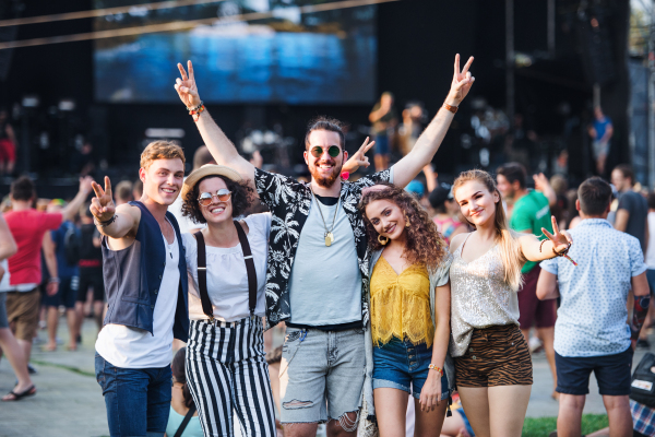 Group of cheerful young friends at summer festival, looking at camera.