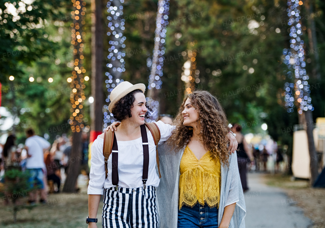 Portrait of two cheerful young women friends at summer festival, walking.