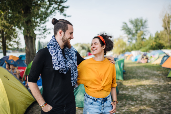 Front view portrait of young couple at summer festival, walking arm in arm.