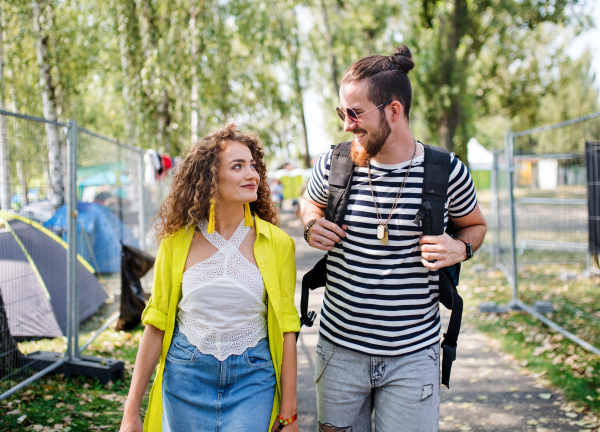 Young couple at summer festival or camping holiday, walking and talking.