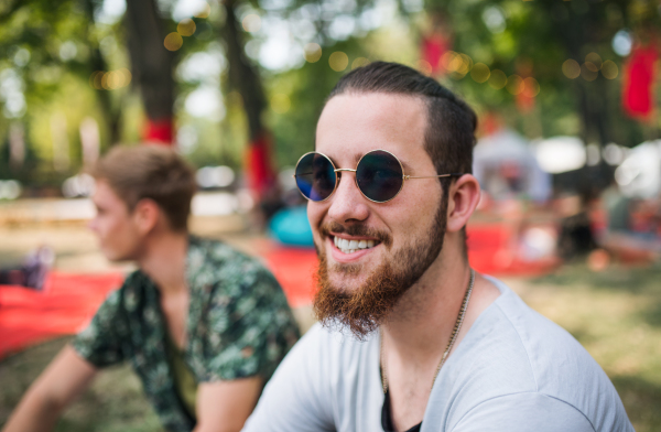 Front view of young man sitting at summer festival. Copy space.