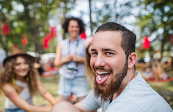 Group of young friends sitting on ground at summer festival, drug dealing concept.