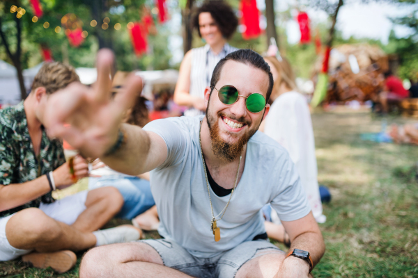 Front view of young man with group of friends at summer festival, having fun.