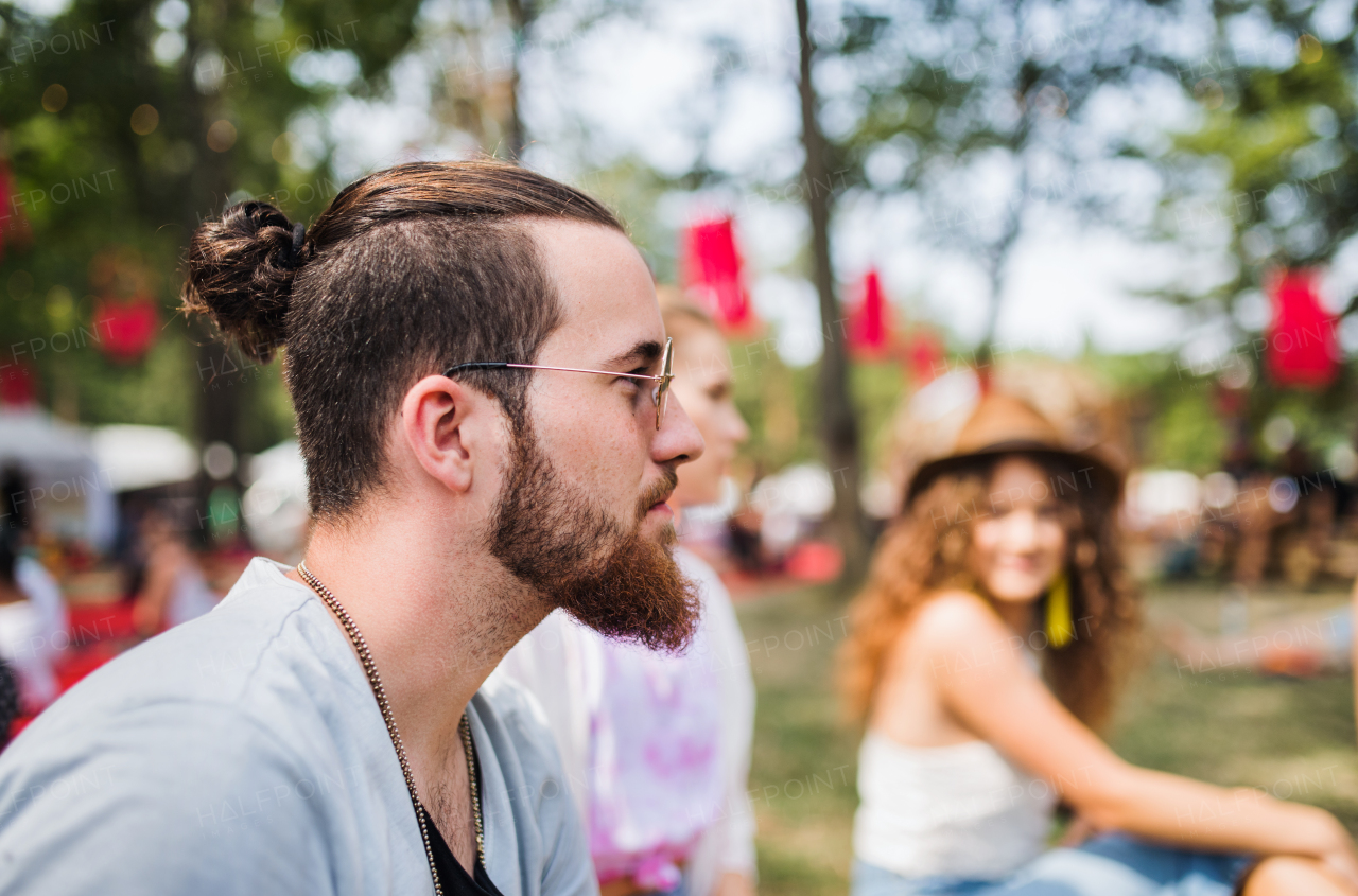 Side view of young man sitting at summer festival. Copy space.