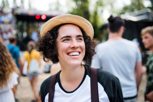 Portrait of beautiful young woman with hat standing at summer festival.