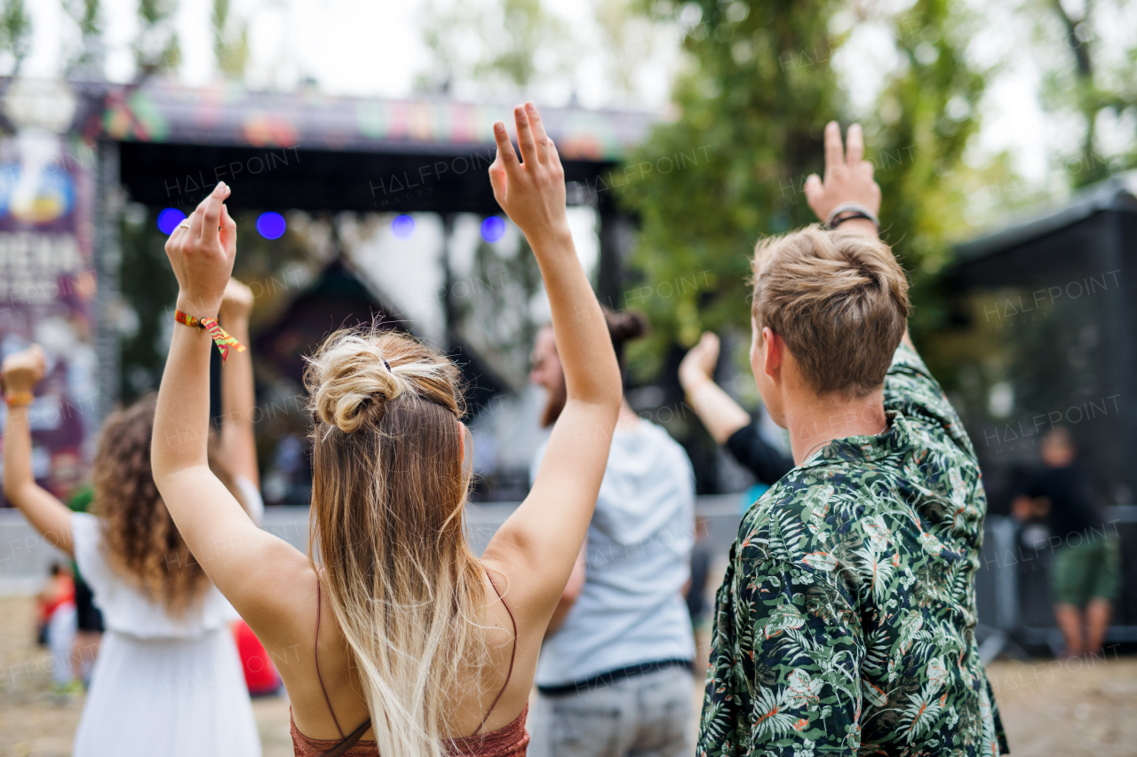 Rear view of group of unrecognizable young friends dancing at summer festival.