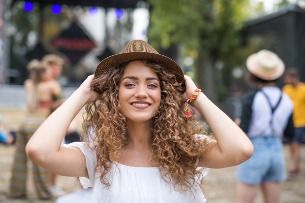 A young woman with hat at summer festival, looking at camera.