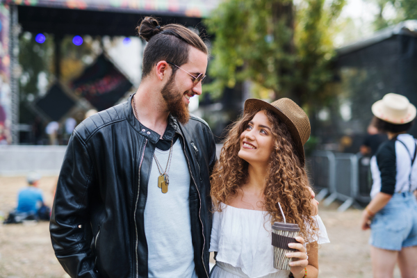 Front view portrait of young couple at summer festival, walking arm in arm.