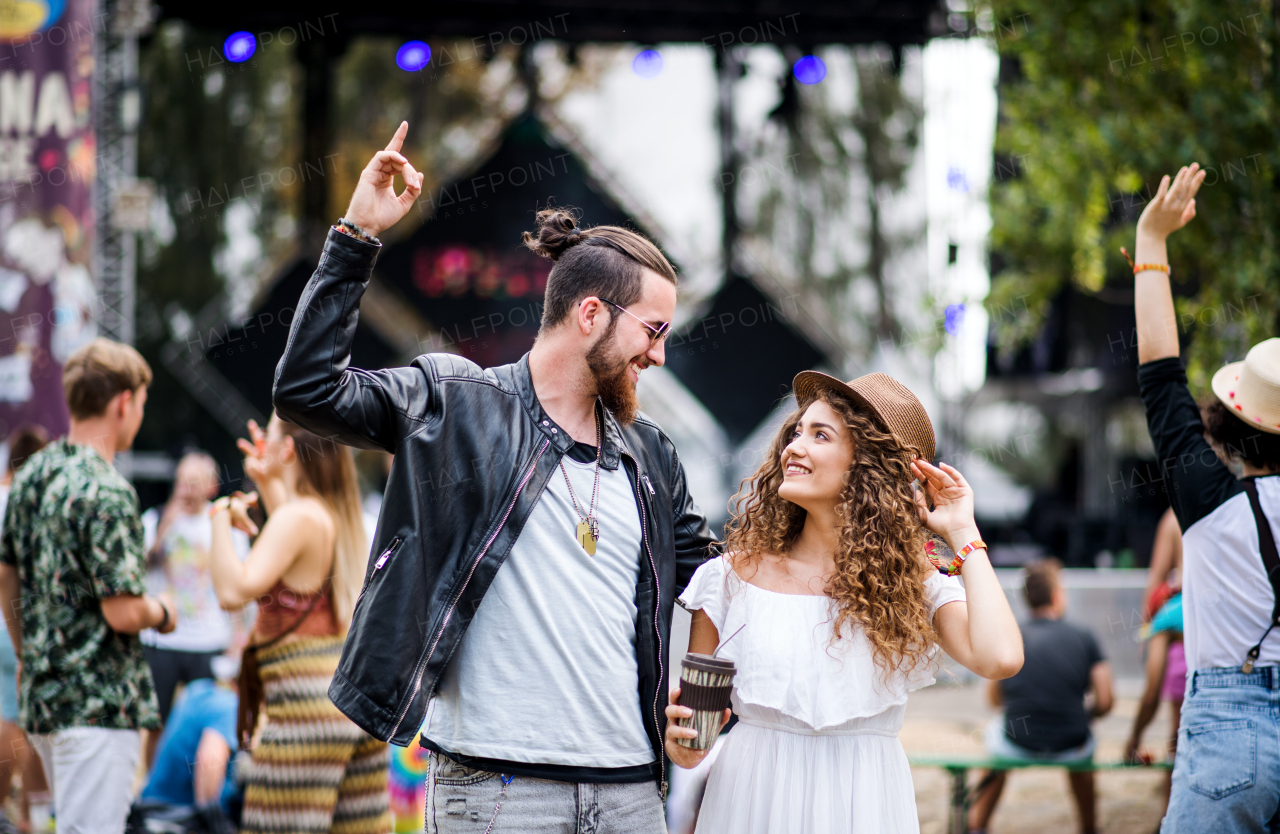 Front view of young cheerful couple at summer festival, dancing.