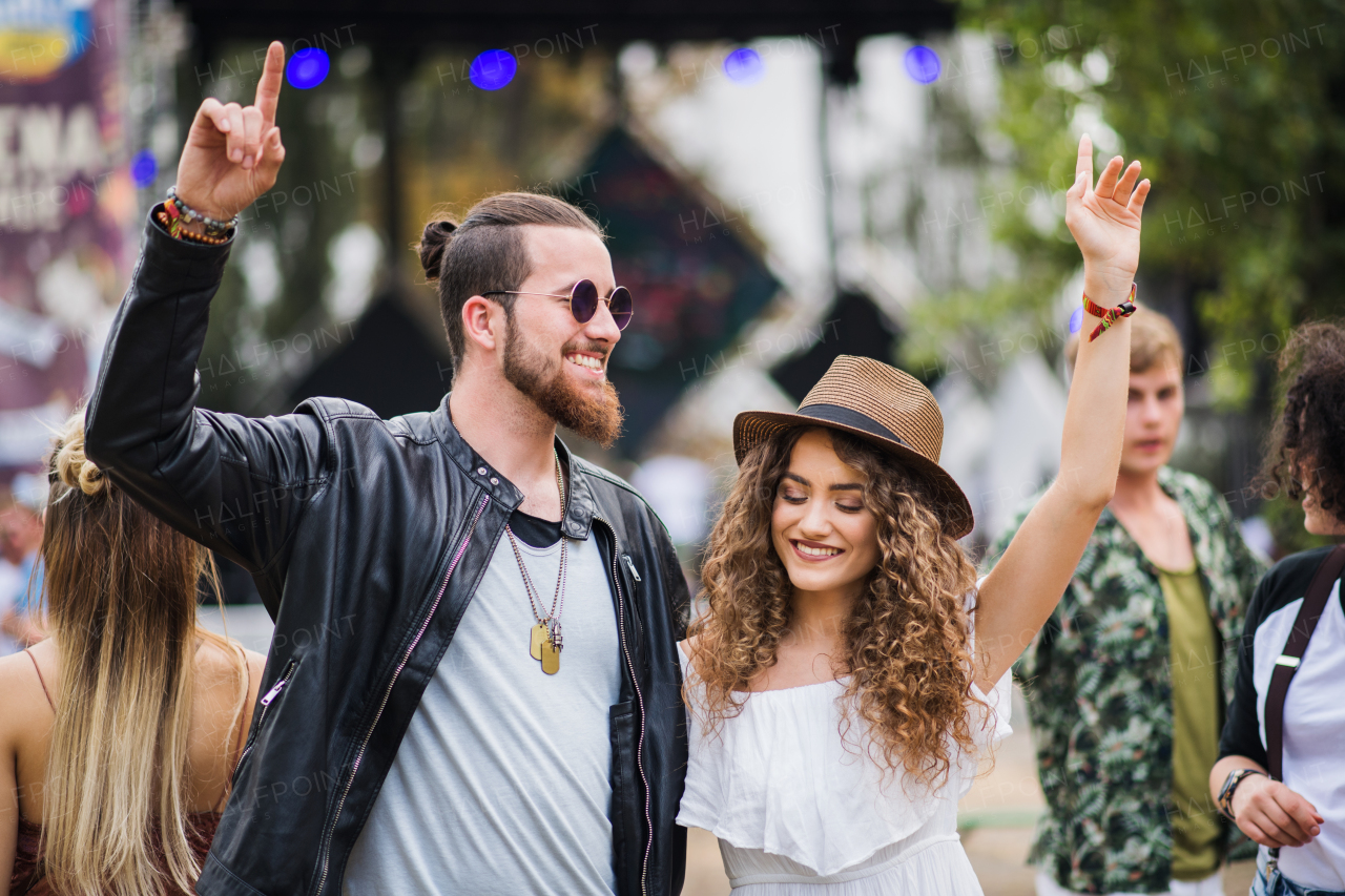 Front view portrait of young couple at summer festival, dancing arm in arm.