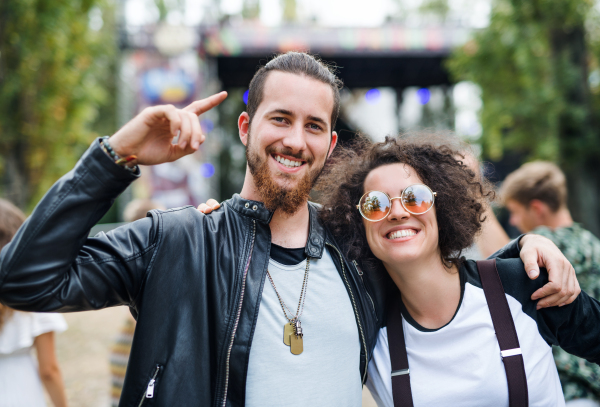 Front view portrait of young couple at summer festival, walking arm in arm.