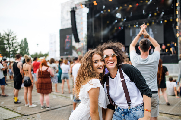 Young girl friends at summer festival, posing for photograph. Copy space.