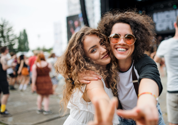 Young girl friends at summer festival, posing for photograph. Copy space.