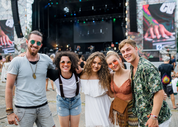 Group of cheerful young friends at summer festival, looking at camera.