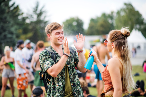 Young couple at summer festival, having fun spraying weather.