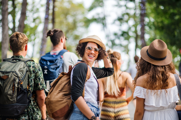 Rear view of group of young friends at summer festival or camping holiday, walking.