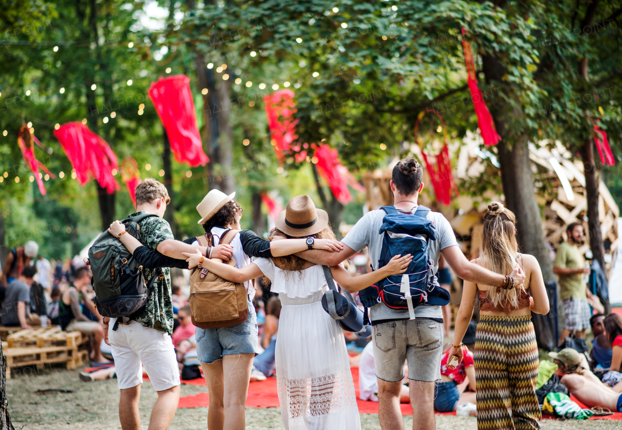 Rear view of group of young friends at summer festival or camping hoiday, walking.