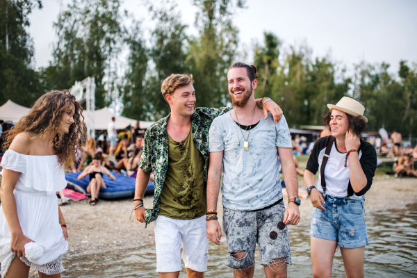 Group of wet young friends at summer festival, standing in lake and looking at camera.