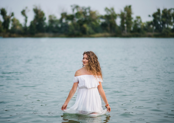 Front view of young woman at summer festival, standing in lake. Copy space.