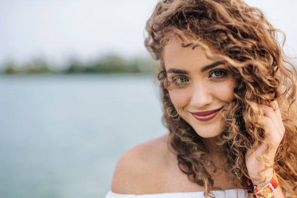 Front view portrait of young woman standing outdoords in summer. Copy space.