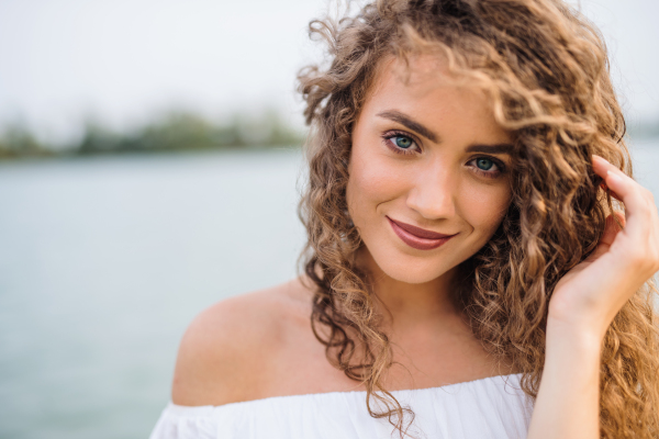 Front view portrait of young woman standing outdoords in summer. Copy space.