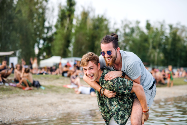 Cheerful young men friends having fun at summer festival, standing in lake.