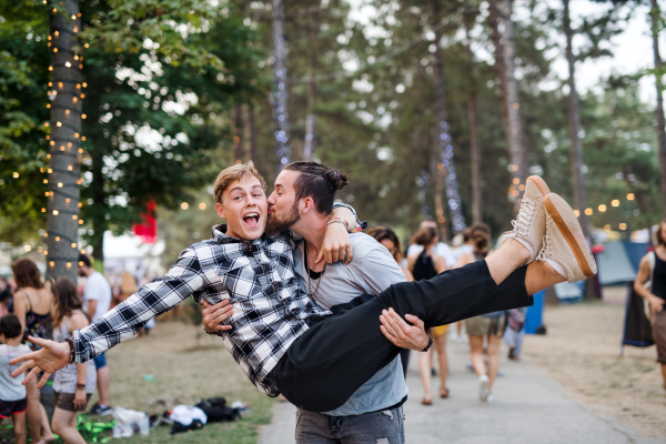 Two cheerful young men friends at summer festival, having fun.