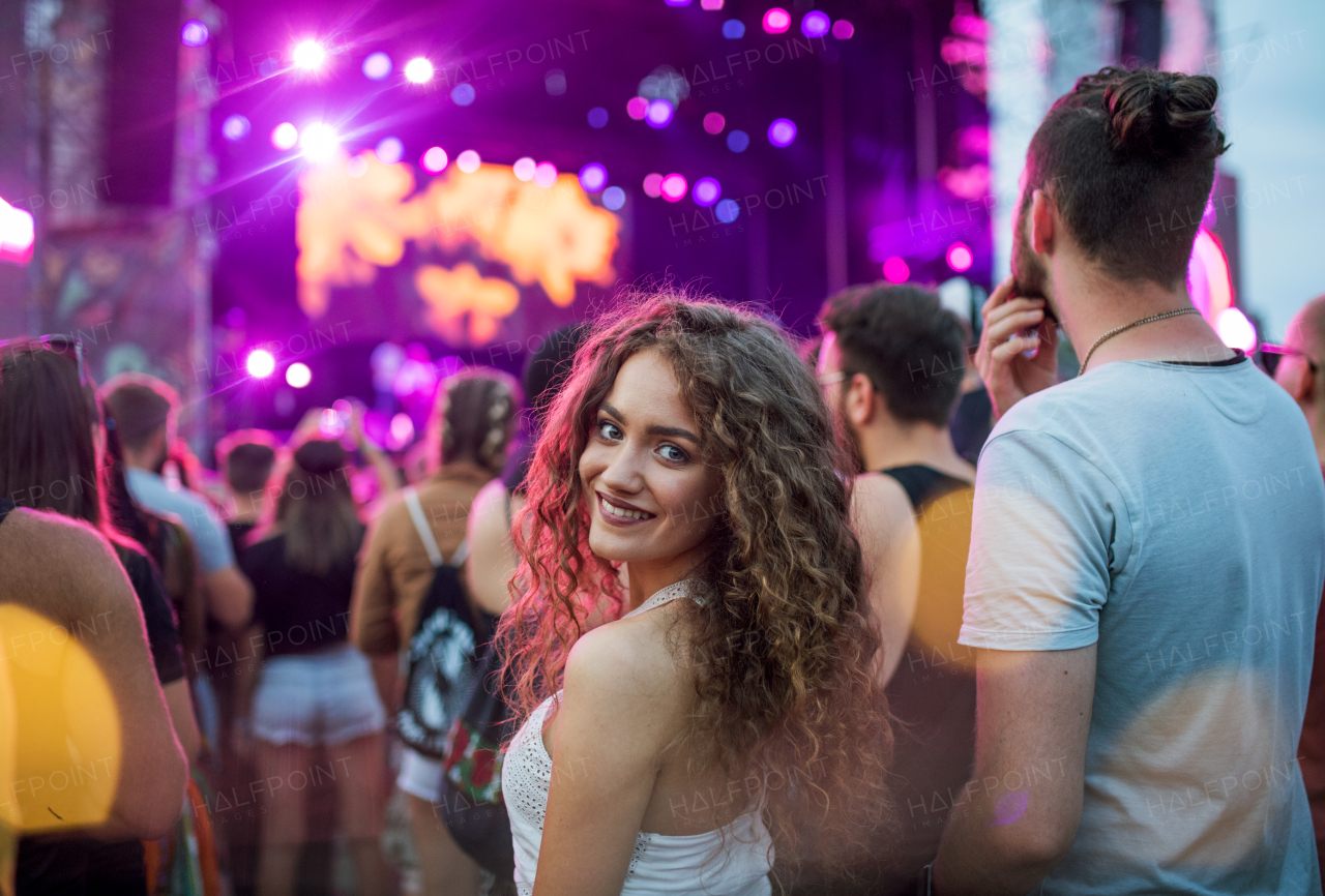 A beautiful young woman standing at summer festival, looking at camera.