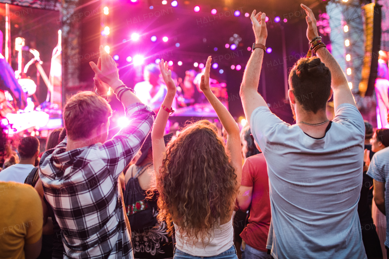 Rear view of group of unrecognizable young friends dancing at summer festival.