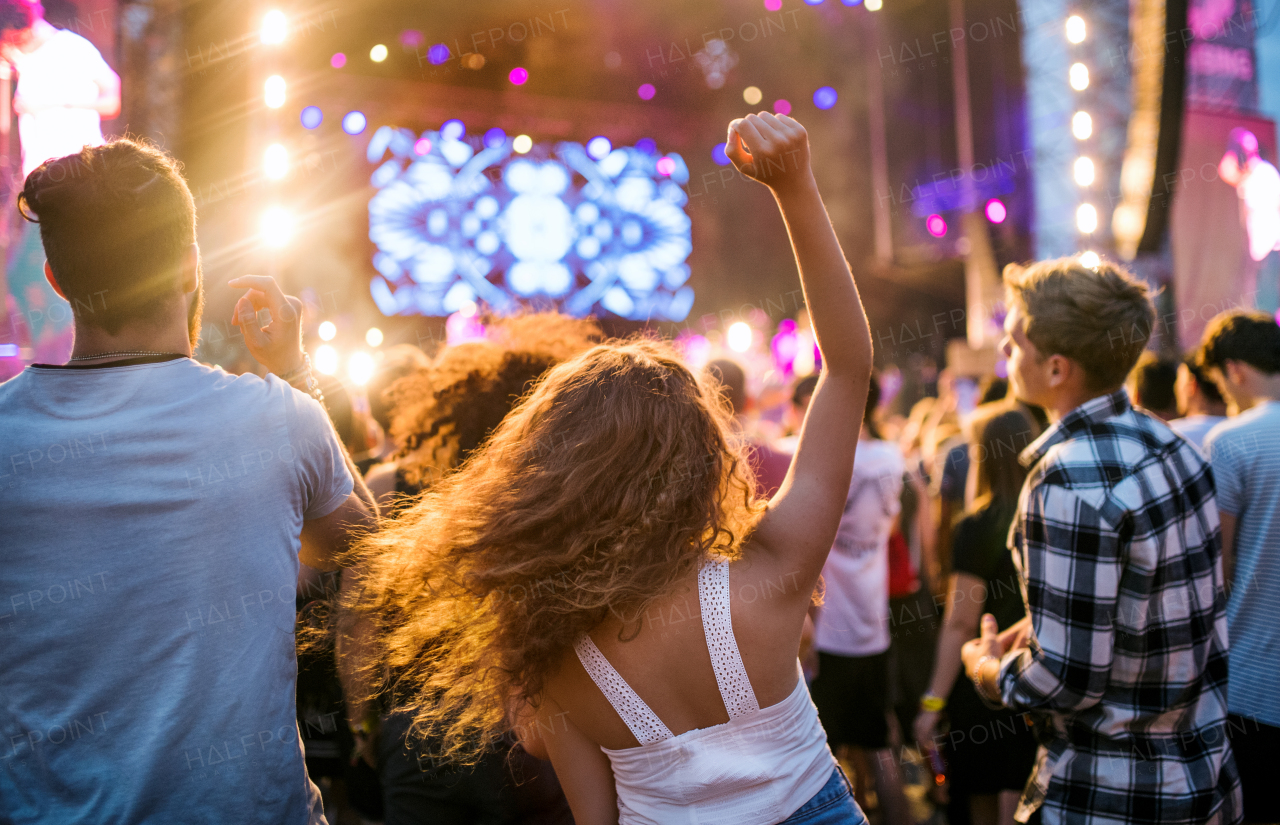 Rear view of group of unrecognizable young friends dancing at summer festival.