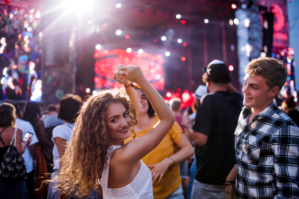 Rear view of group of cheerful young friends dancing at summer festival.