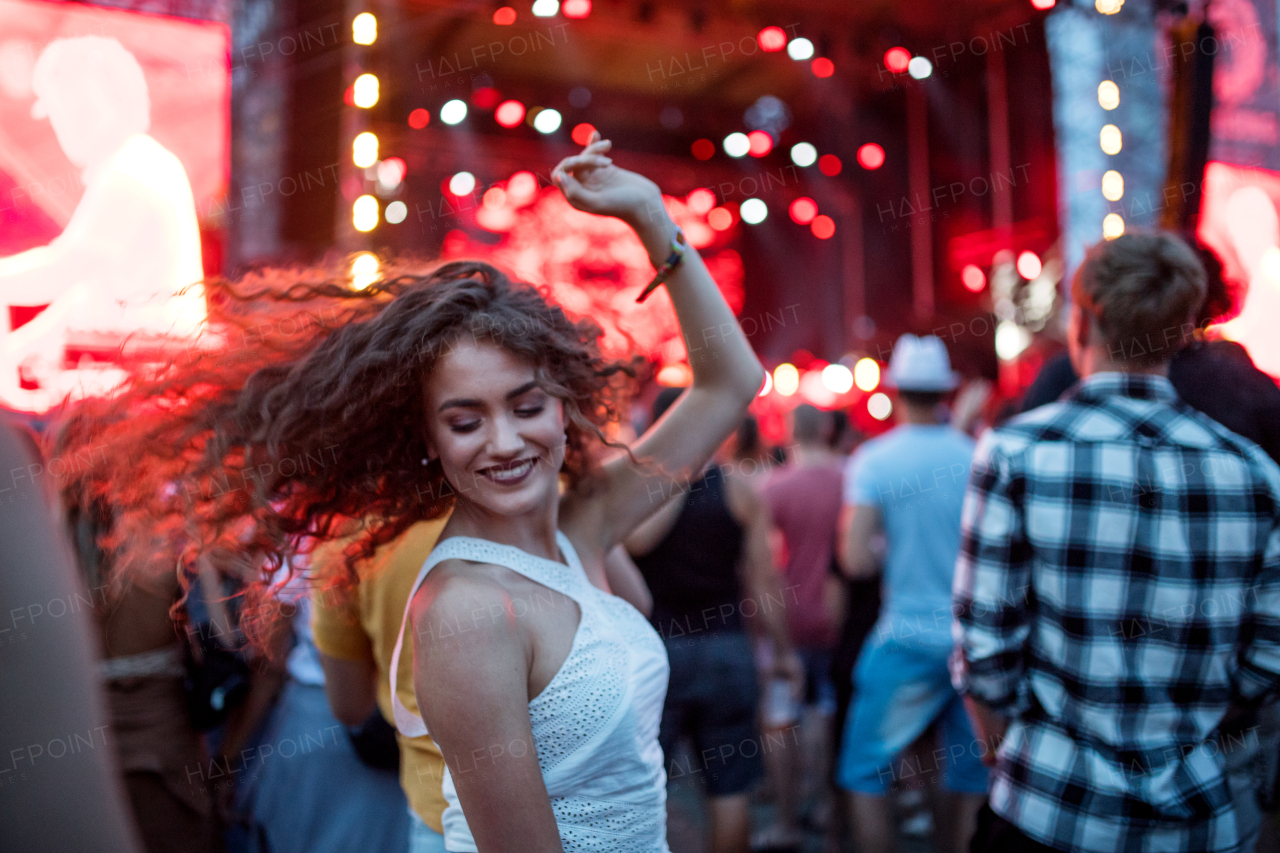 Beautiful young woman with friends dancing at summer festival.