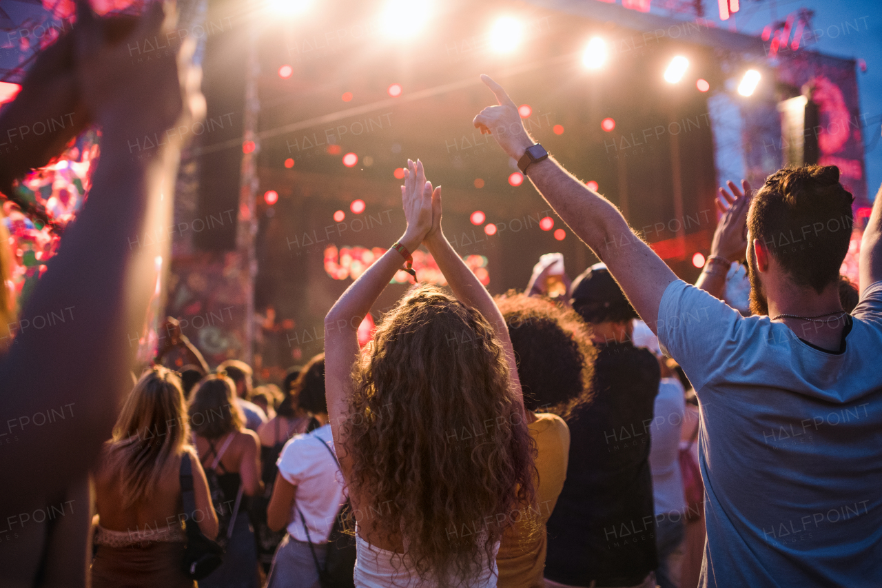 Rear view of group of unrecognizable young friends dancing at summer festival.