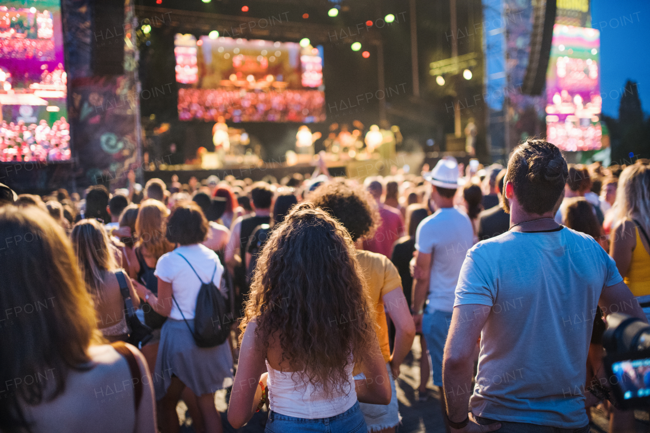 Rear view of group of unrecognizable young friends at summer festival.