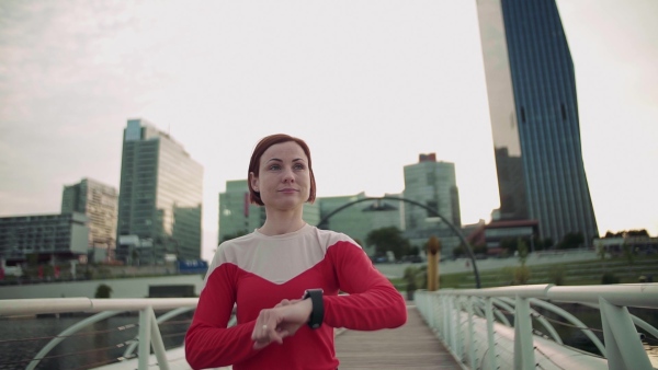 Young woman with smartwatch on bridge outdoors in city, resting after exercise. Slow motion.