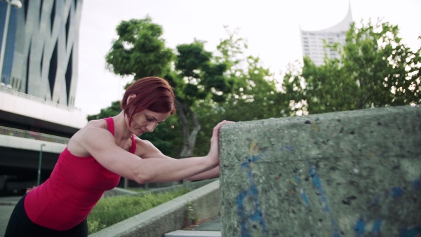 Young woman doing exercise outdoors in city, stretching. Slow motion.